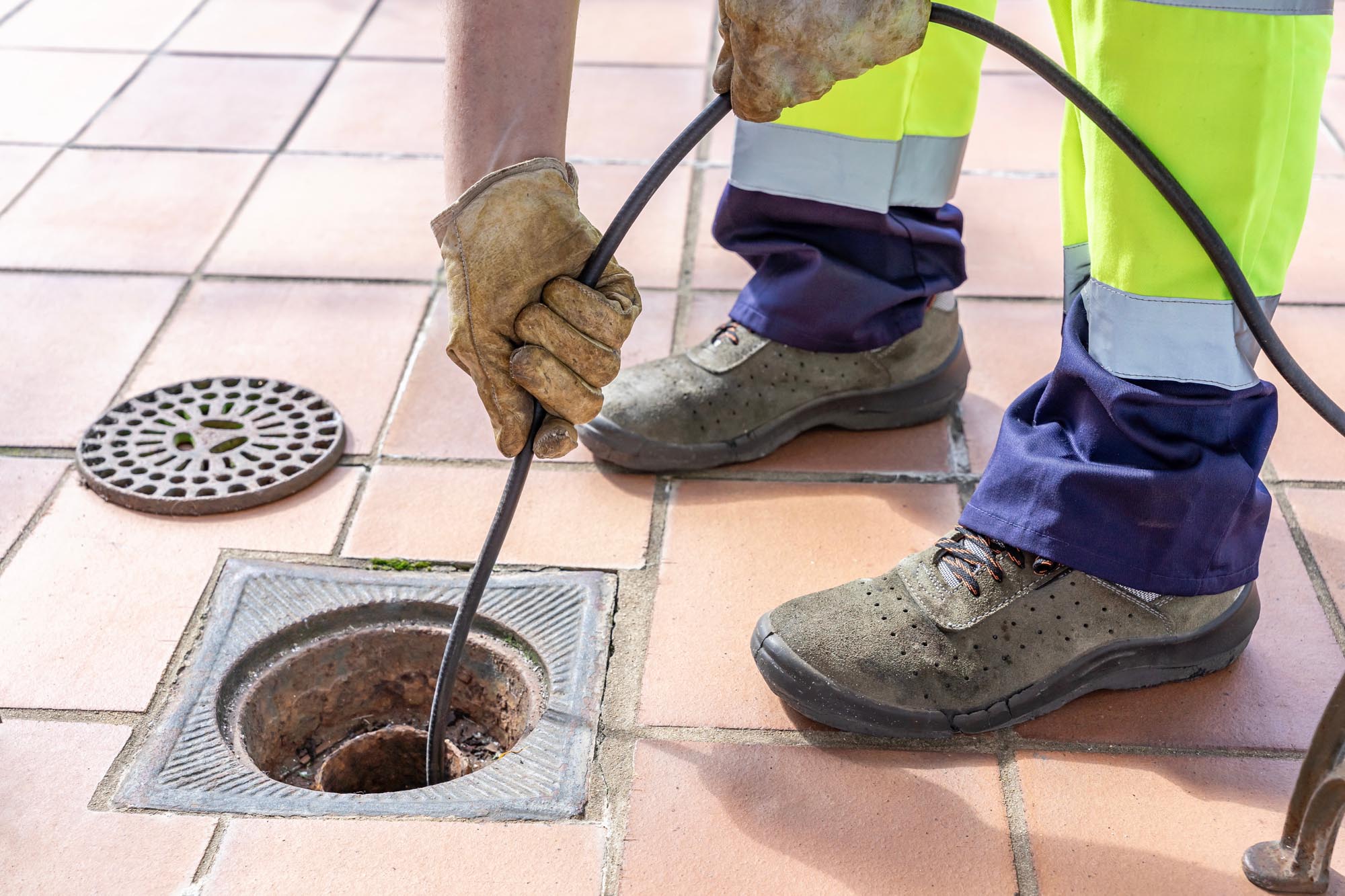 Sewer worker unclogging blocked yard drain with hydro jetting ho