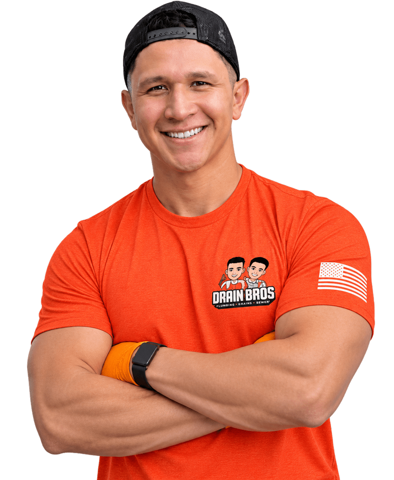 Smiling Drain Bros technician with arms crossed wearing a branded orange shirt and black hat.